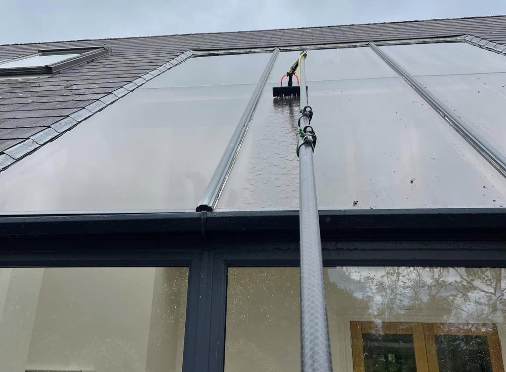 roof glass being cleaned with a long extension glass cleaner.